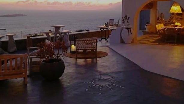 An outdoor terrace with seating and tables, overlooking the sea at sunset. - Vougli View (Mykonos)