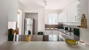 Una cocina moderna con armarios blancos, un refrigerador de doble puerta, horno integrado y un ventanal que proporciona luz natural.