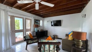 Un amplio salón con ventilador de techo, televisor y sofá.