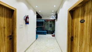 A hallway with wooden doors, a fire extinguisher, and a number sign. - Hotel Shree Mahakal Krapa (Ujjain)