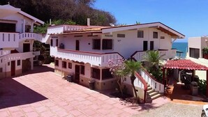 A two-story building with a balcony, a staircase, and a small garden area. - Casa las Mariposas Bungalow 9 (Los Ayala)