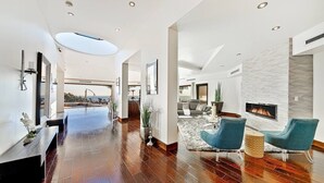 A spacious living area with a fireplace, a pool, and a view of the outdoors.