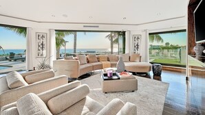 A modern living room with a large sectional sofa, a coffee table, and a view of the ocean.