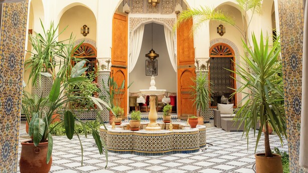 A courtyard with tiled flooring, arches, and potted plants. - Riad Al Ansari (Fes)