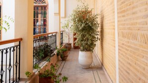 A corridor with arches, potted plants, and a hanging lantern. - Riad Al Ansari (Fes)