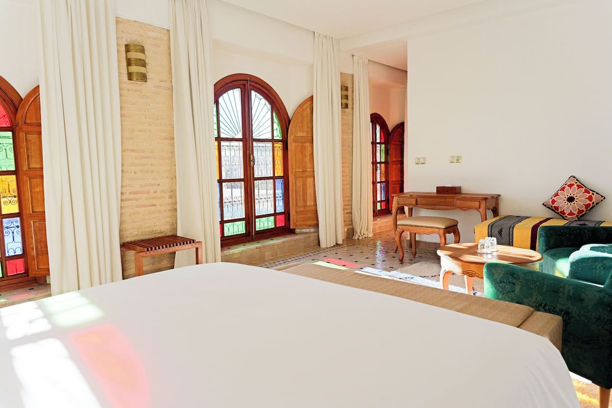 Ein Hotelzimmer mit einem großen Bett, Holzmöbeln und Buntglasfenstern.