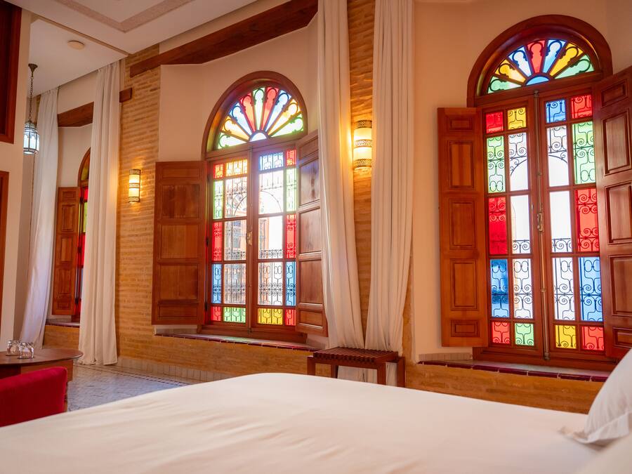 Een hotelkamer met een groot bed, houten wanden en glas-in-loodramen.