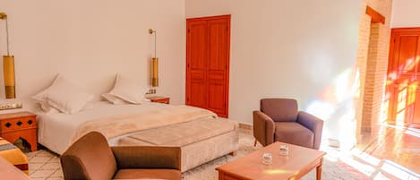 A bedroom with a bed, a sofa, a coffee table, and a nightstand.