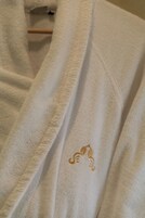 Uma toalha branca com logo dourado bordado.