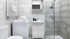 A modern bathroom with a toilet, a radiator, a sink, and a shower. - EASY RENT Apartments - Smart 005 (Lublin)