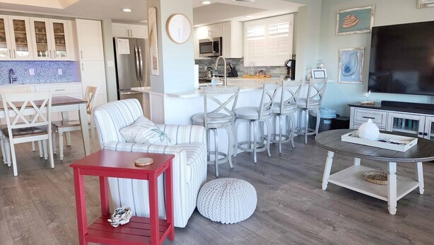 A modern living room with a sofa, chairs, a red table, and a TV. - Inlet Point 14A offers Beautiful Marsh Views and Easy Creek Access (Pawleys Island)