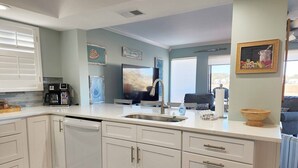 A modern kitchen with white cabinets, a built-in dishwasher, and a large window. - Inlet Point 14A offers Beautiful Marsh Views and Easy Creek Access (Pawleys Island)
