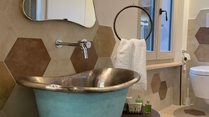 A bathroom with a freestanding bathtub, a mirror, a towel rack, and a toilet. - MontepulcianoLettings (Montepulciano)