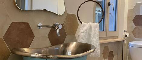 Een badkamer met een vrijstaand bad, een spiegel, een handdoekhouder en een toilet.