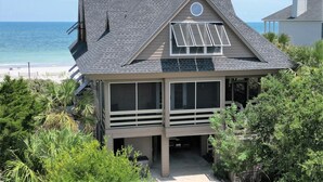 Une maison de plage moderne dotée d’un grand balcon, d’un panneau solaire et offrant une vue sur l’océan.