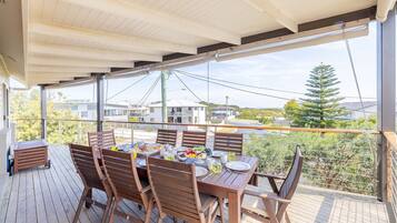 A covered outdoor dining area with a table set for four, surrounded by wooden chairs.