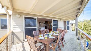 A covered outdoor dining area with a wooden table set for four, surrounded by chairs.