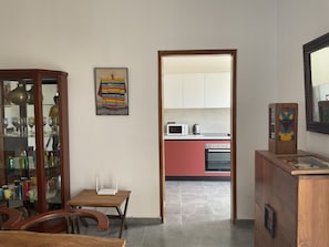 Cozinha com armários vermelhos, micro-ondas e fogão. Há um armário de madeira com portas de vidro à esquerda, e um quadro na parede.