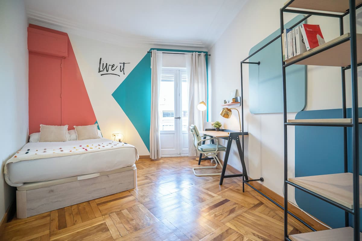 Un dormitorio con cama, escritorio y estantería.