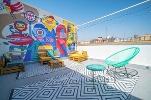 A rooftop terrace with colorful murals, wooden furniture, and a patterned floor. - Live It Madrid Chamberi (Madrid)