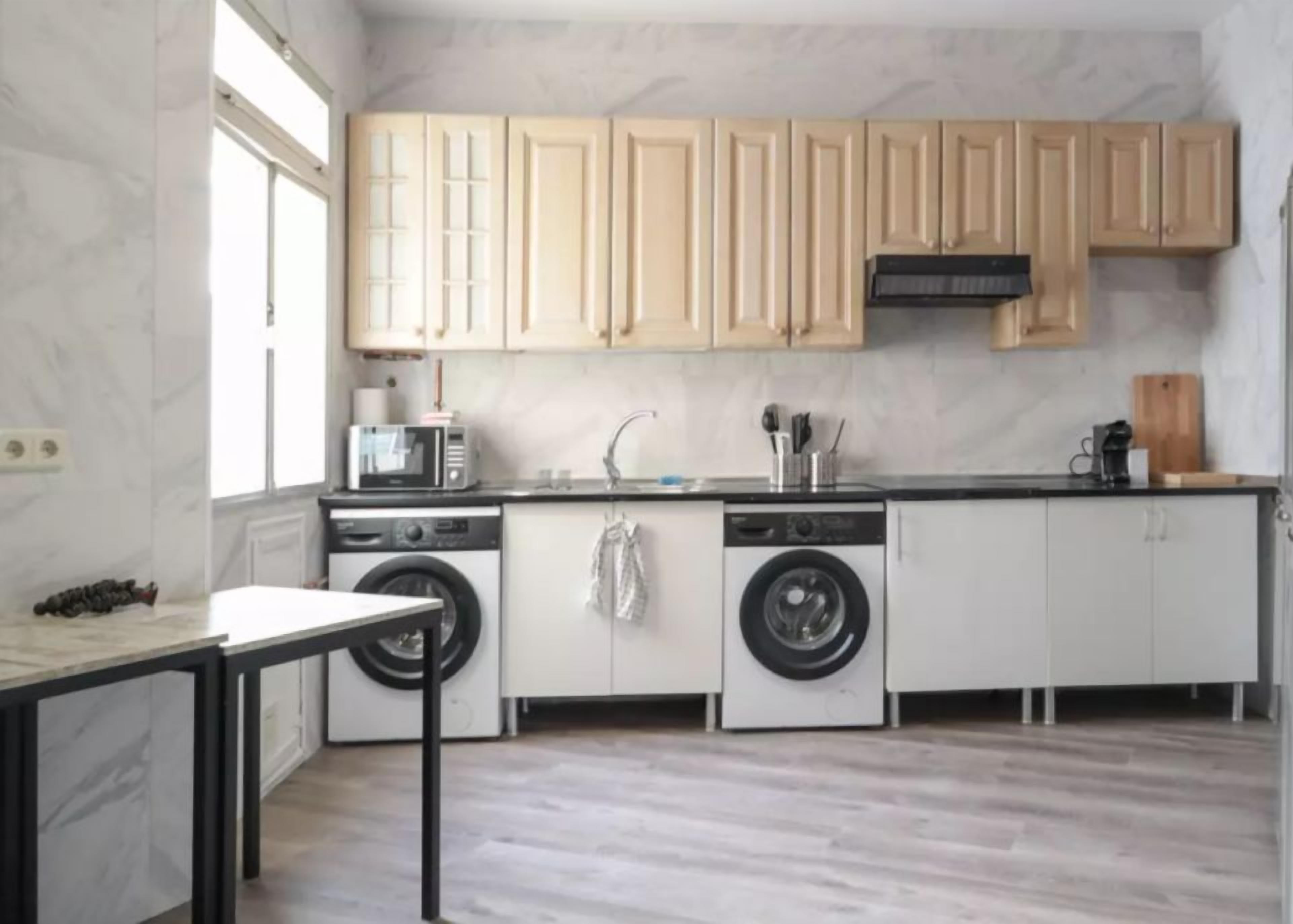 A compact kitchen with a washing machine, a coffee maker, and a sink.