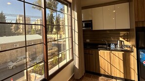 A modern kitchen with a large window, a hanging light fixture, and a view of the street outside. - Antica Jabalal-lwebdeh 5 (Amman)