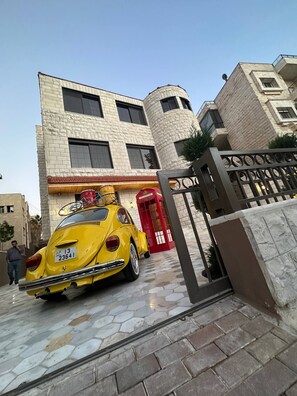 Une voiture jaune est garée devant un immeuble avec une porte rouge et un portail.