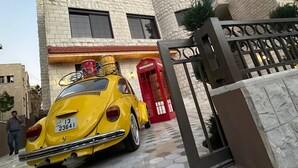 Un coche amarillo estacionado frente a un edificio con puerta roja y portón.