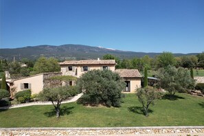 A stone house with a tiled roof, surrounded by a well-maintained lawn and trees, with a mountain in the background. - Vacation rental house with pool BEDOIN LS4-435 (Bédoin)