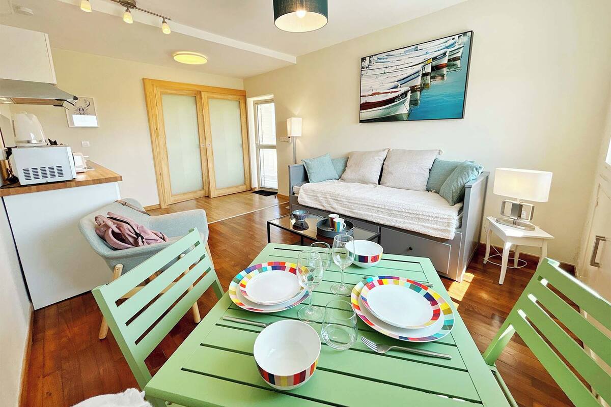Un salon moderne comprenant une table à manger pour quatre personnes, un canapé, un tableau et un coin cuisine.