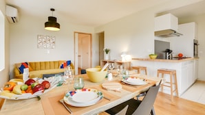Una cocina moderna con una mesa de comedor preparada para cuatro personas, un tazón amarillo y diversos utensilios de cocina.