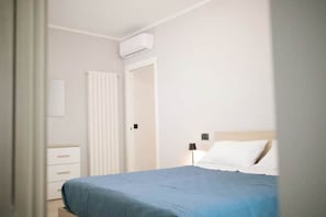 Une chambre à coucher avec un lit, une table de chevet, une lampe et une armoire.