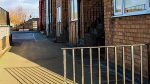 A row of brick buildings with large windows, a metal fence, and a clear sky. - Lovely 2-bed Apartment in Sutton Coldfield (Sutton Coldfield)