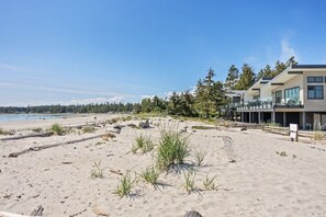 A beachside hotel with modern architecture, a sandy beach, and a view of the ocean.
