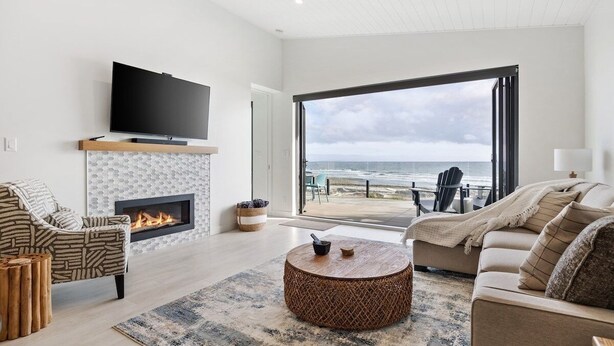 A modern living room with a fireplace, a flat-screen TV, a round coffee table, and a sofa.