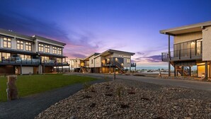 A modern residential building with multiple balconies, a well-maintained garden, and a view of the ocean.