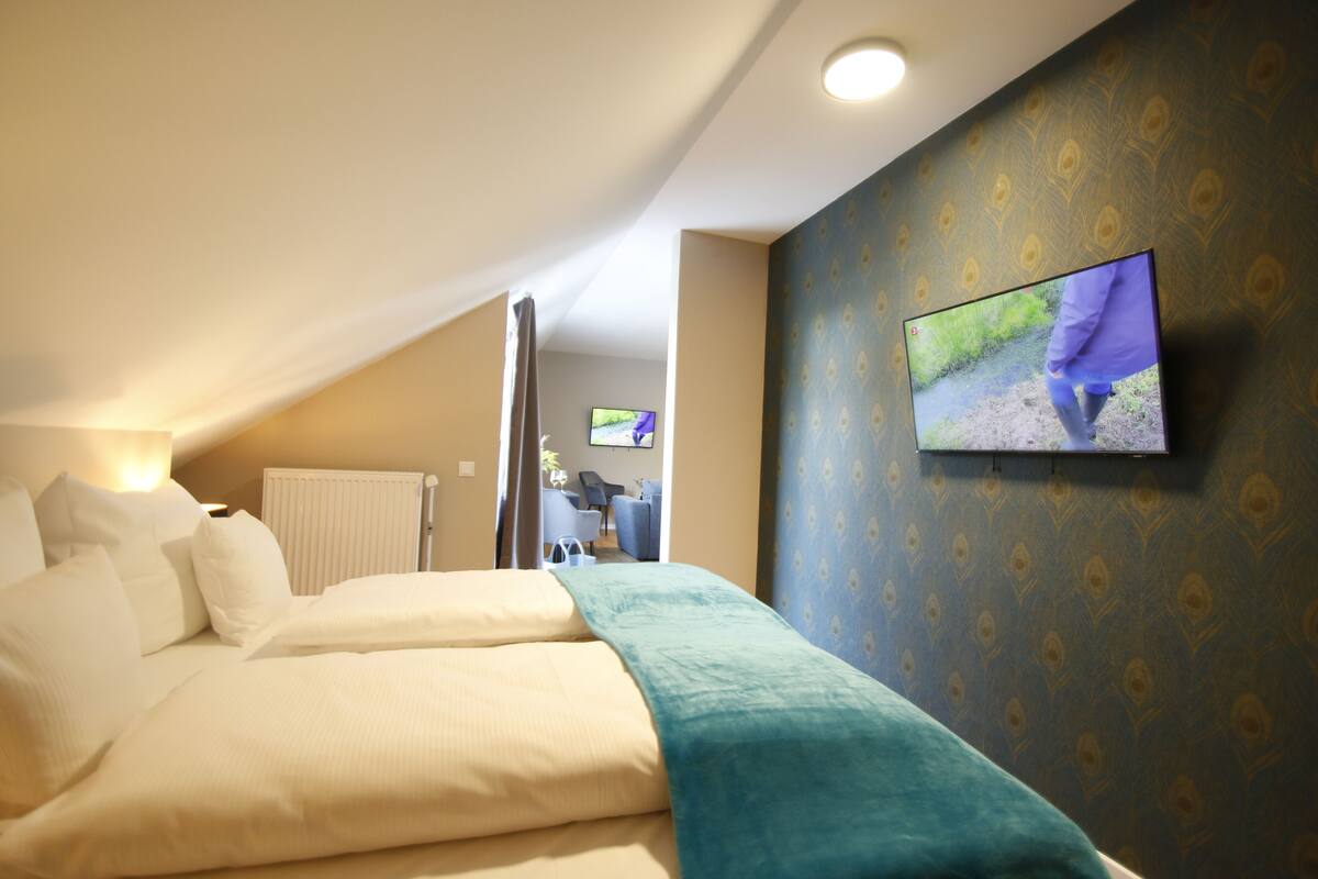 Una habitación de hotel con una cama, un televisor montado en la pared y vistas al pasillo.