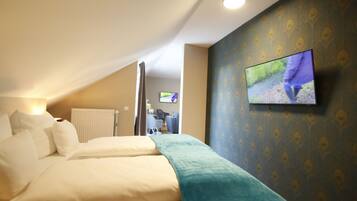 A hotel room with a bed, a television mounted on the wall, and a view of the hallway.