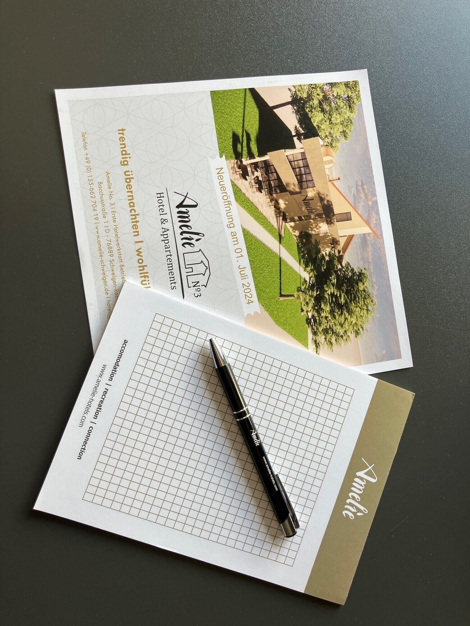 Une carte de visite et une brochure d’hôtel avec une présentation en grille, ainsi qu’un stylo.