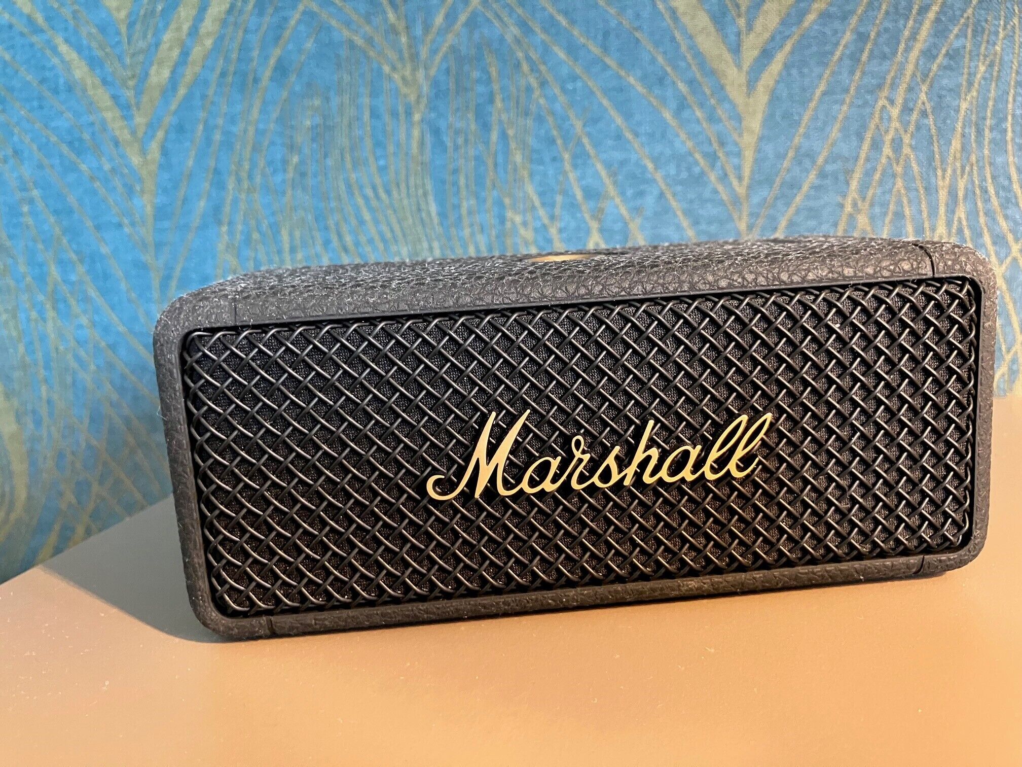A black Marshall speaker with a textured surface and the brand name in gold lettering.