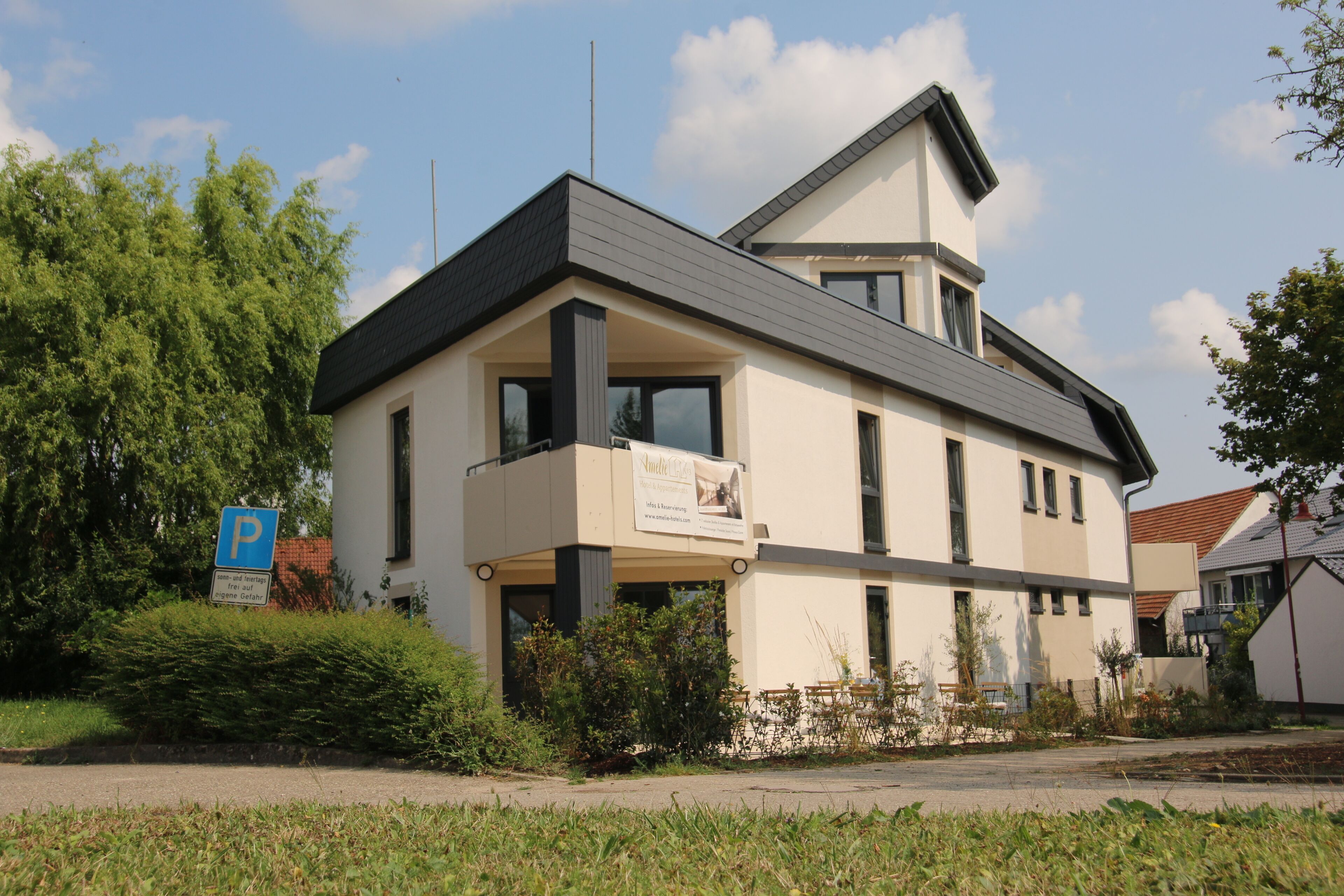 Un bâtiment moderne à deux étages, doté d’un toit plat, de grandes fenêtres et d’une enseigne bien visible indiquant un espace de stationnement.