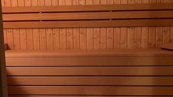 Un sauna en bois, doté de bancs et d’un thermomètre fixé au mur.