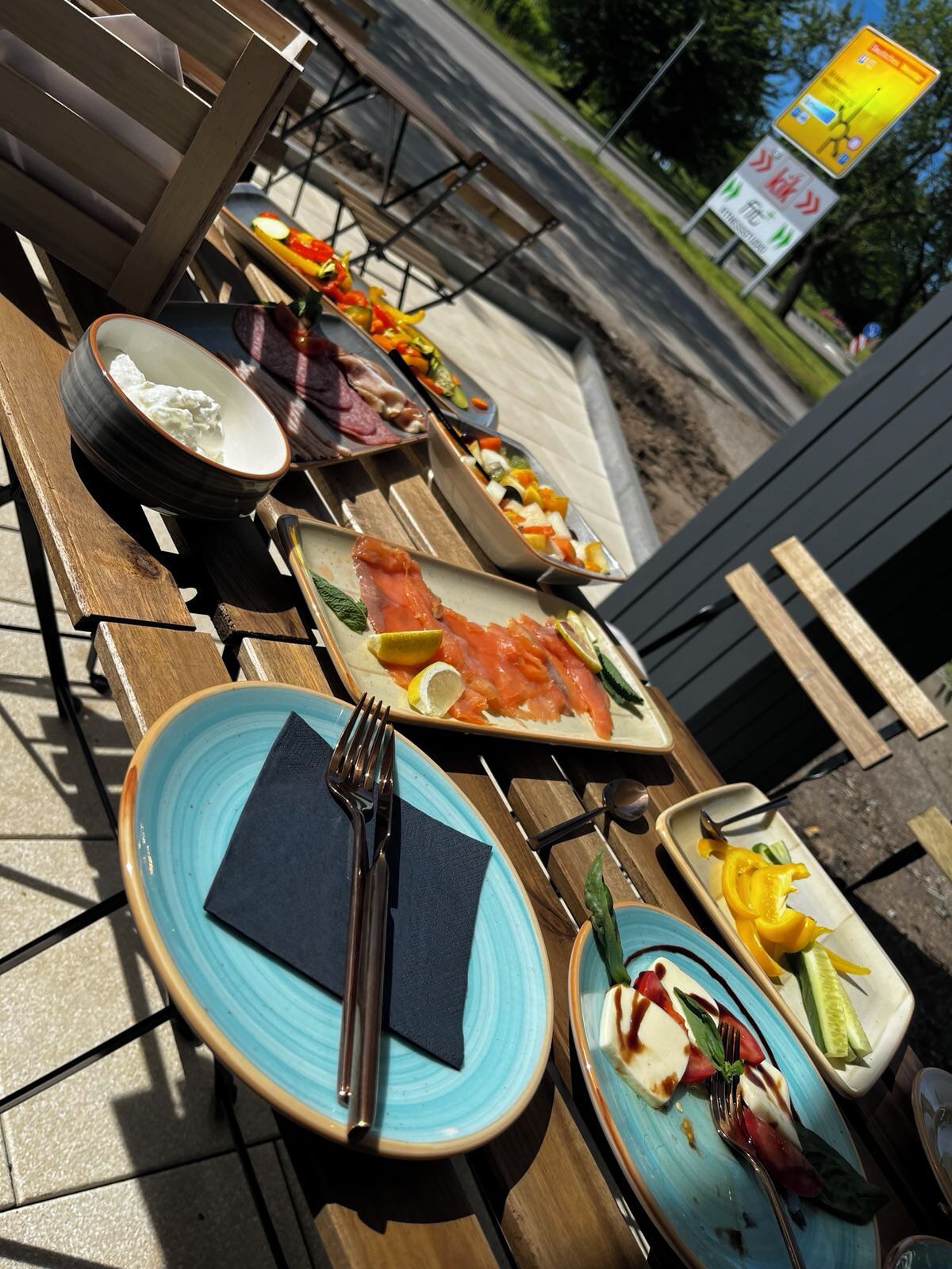 A table set with various dishes, including a bowl of soup, a plate of smoked salmon, and a dish with vegetables and cheese.