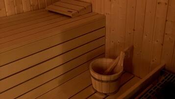 A sauna room with wooden benches, a wooden bucket, and a ventilation system.