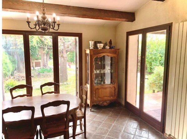 Enjoy meals in this dining area with a wooden table and chairs, a chandelier, and a cabinet with glass doors, offering a view of the outdoors.