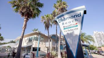 A hotel sign with 'Diamond Beach BreakFree Quality Resort' and palm trees.