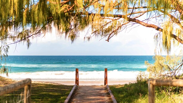 Un sendero de madera que conduce a una playa con vistas al océano.