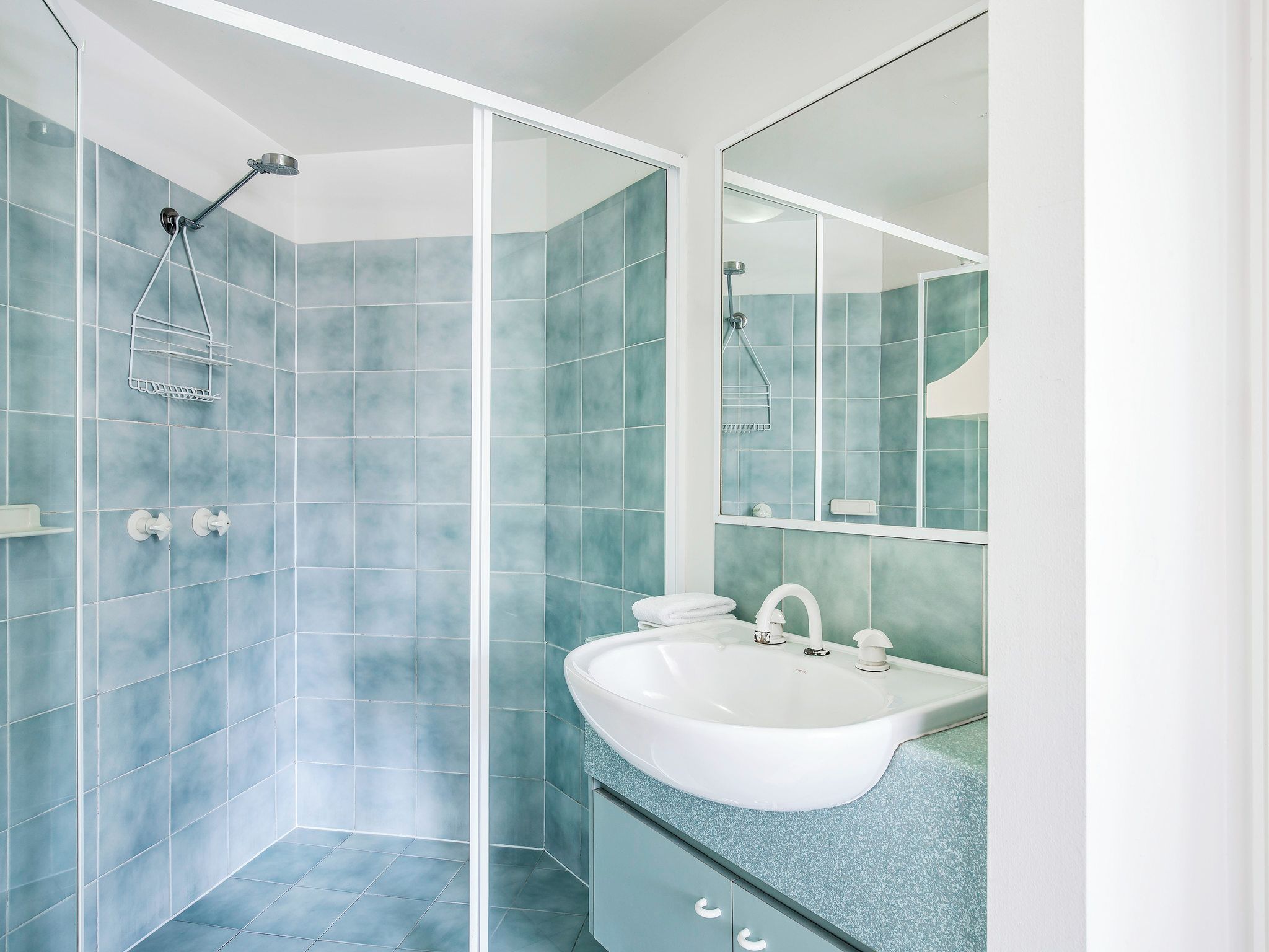 A modern bathroom with a shower, a sink, and a mirror.
