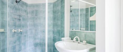 A modern bathroom with a shower, a sink, and a mirror.