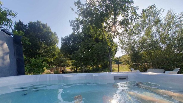 A hot tub surrounded by trees and a wooden fence.